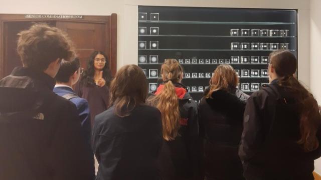 A St Catharine's student ambassador shows visiting students a periodic table sci-art installation