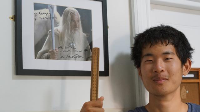 Alex Gao stands in front of a signed photo of Sir Ian Mckellen