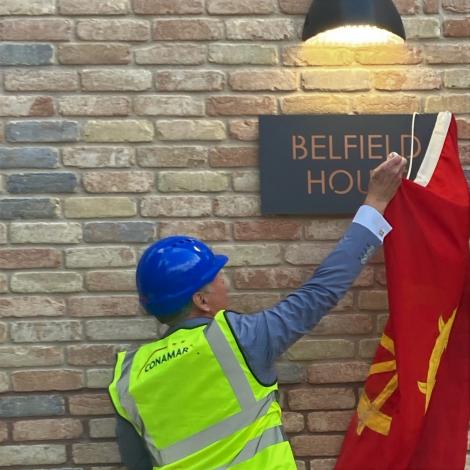 Professor Sir Mark Welland removes the St Catharine's College flag to reveal a sign naming Belfield House