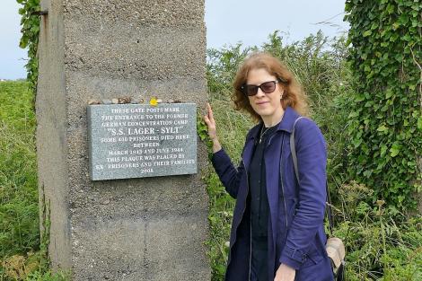Dr Gilly Carr standing next to the entrance posts of SS Lager Sylt in Alderney