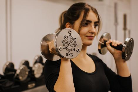 Weights with wheel details being lifted by a St Catharine's student in the College gym