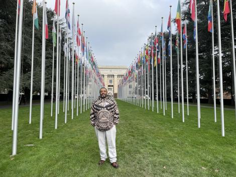 Malik Al Nasir standing with the flags of the member countries of the UN in Geneva
