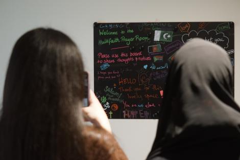 Students photographing a noticeboard in the St Catharine's College multifaith prayer room