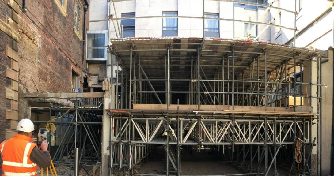 The Central Spaces site is surveyed by a contractor with scaffolding in place of the old Hall